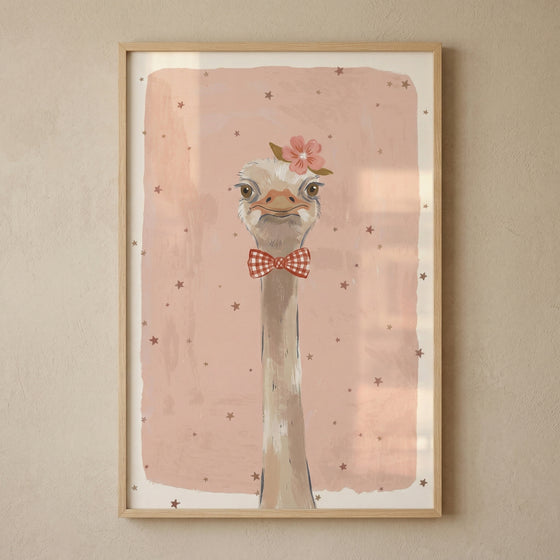 Framed illustration of an ostrich with a long neck wearing a red checkered bow tie and a pink flower on its head against a soft pink background with scattered stars. The playful portrait style artwork adds a lighthearted and whimsical touch to a nursery or child’s room wall.