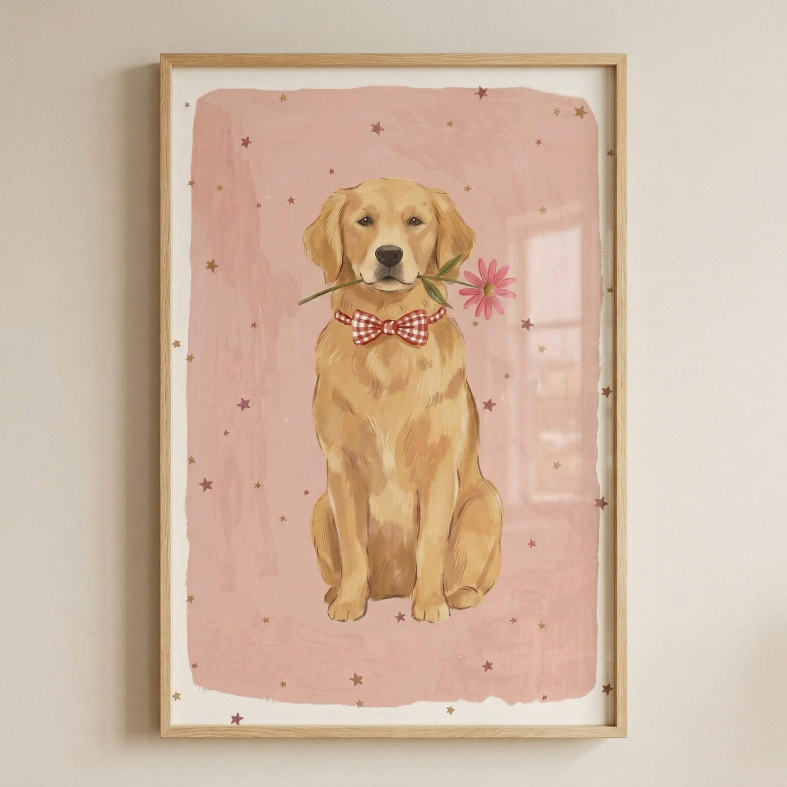 A vertical wooden frame contains a whimsical illustration of a golden retriever sitting patiently and looking forward. The dog is wearing a red and white checkered bowtie and holds a single pink daisy by its stem in its mouth. The background is a soft, textured pink wash decorated with small, scattered brown stars. The overall style is light and gentle with a hand-drawn aesthetic.