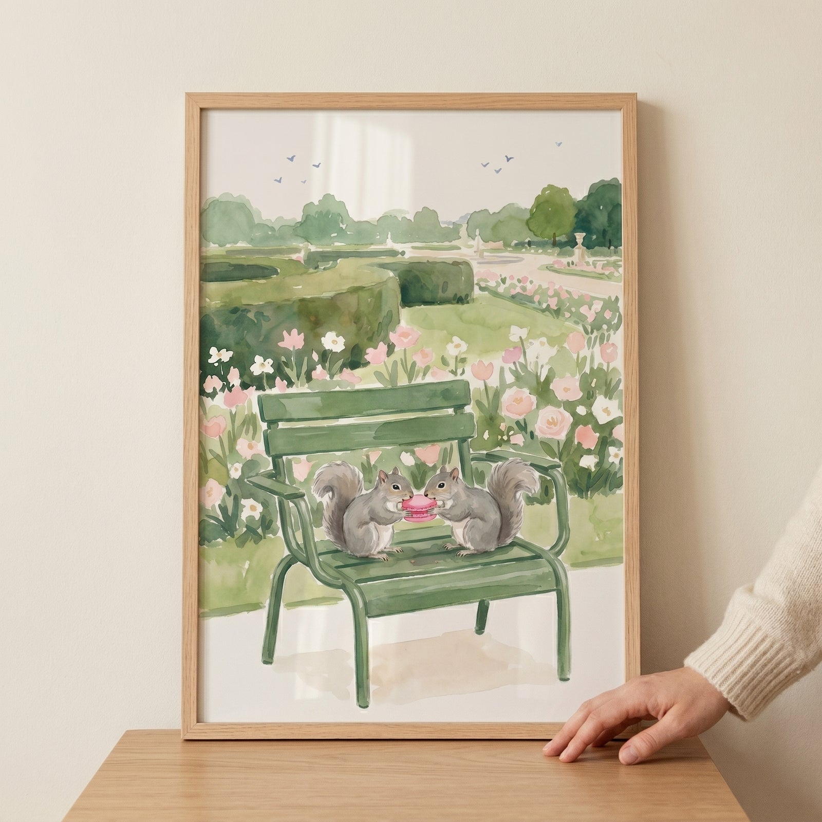 Two squirrels share a snack on a green bench in this pink macaron eating squirrels wall art featuring a floral garden.