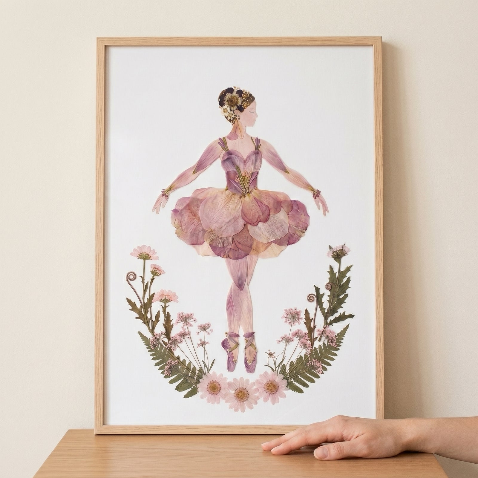 Pink petal tutu ballerina wall art made from pressed flowers and botanicals, displayed in a light wood frame.