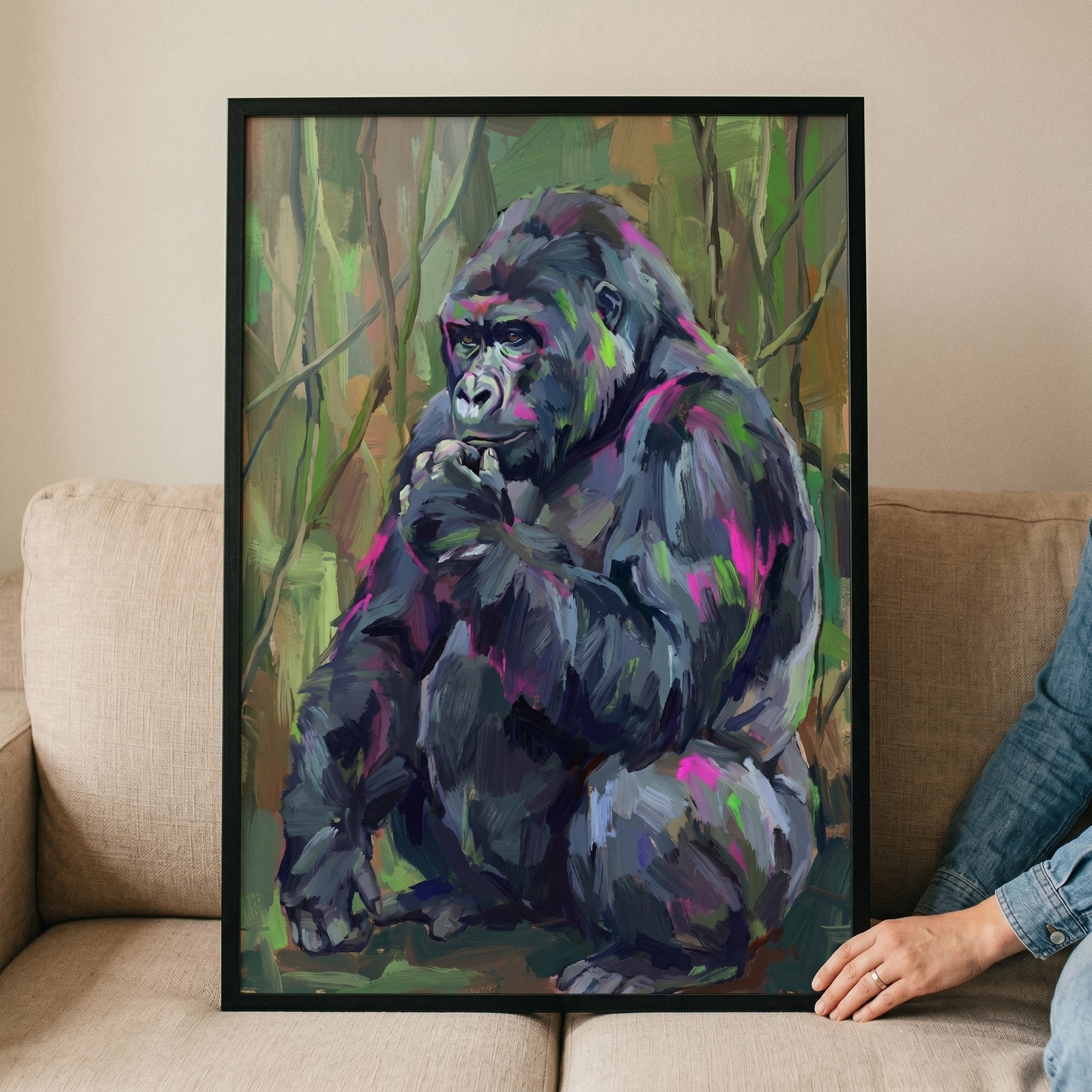 Pink purple textured gorilla artwork in a black frame on a couch, featuring a colorful gorilla in a green jungle.