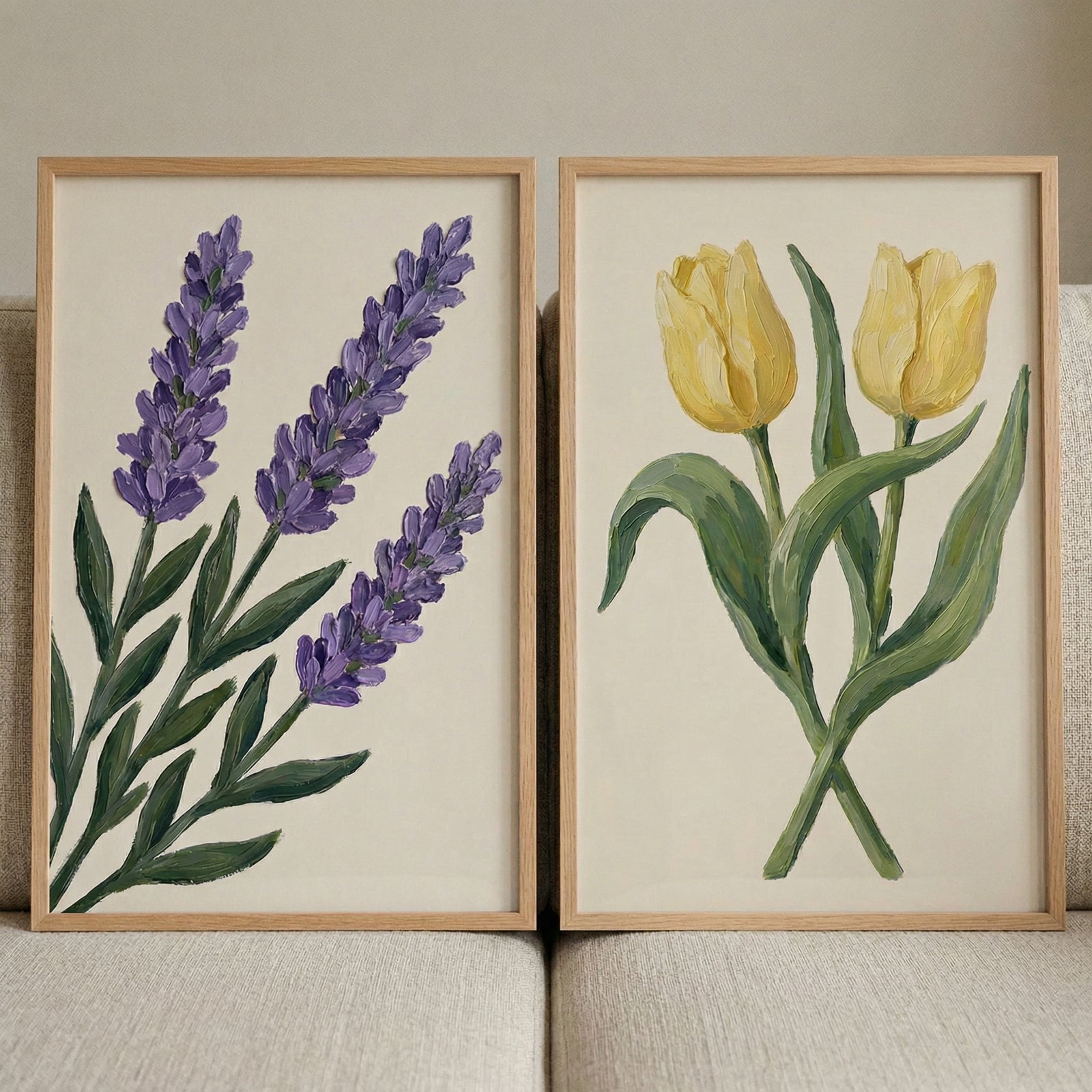 Two framed botanical paintings leaning against a neutral sofa featuring purple lavender stems on the left and two yellow tulips on the right adding soft color and a calm natural touch to the space.