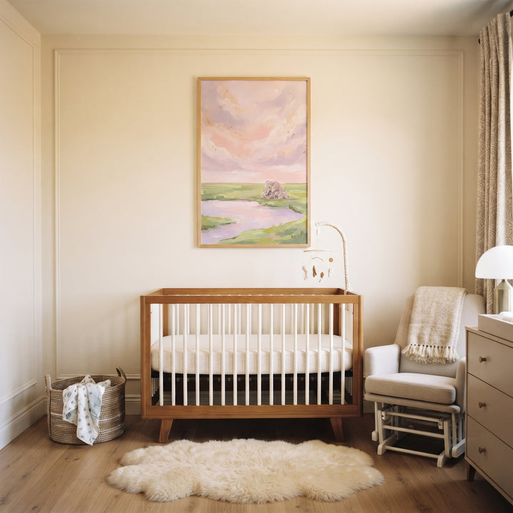 Neutral nursery with a wooden crib, sheepskin rug, and pink sky cuddling elephant animal wall art on a cream wall.