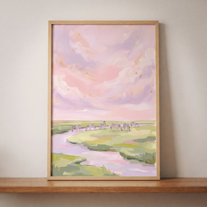 Framed pink sky grazing zebra animal wall art of zebras in a field by a river under a pastel sunset.