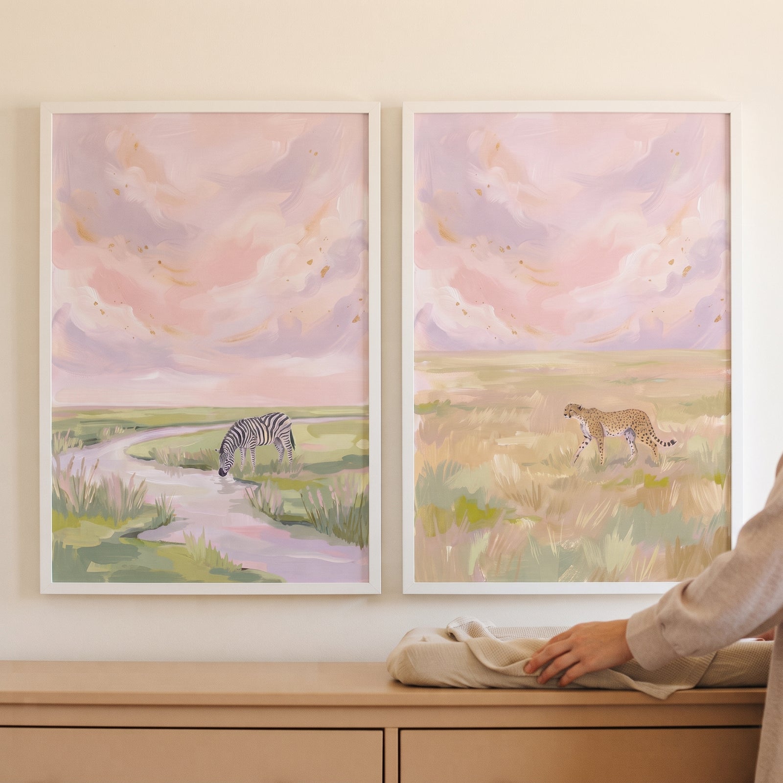 Pink sky safari animals wall art set of 2 shows a zebra and cheetah in soft pastel savanna landscapes.