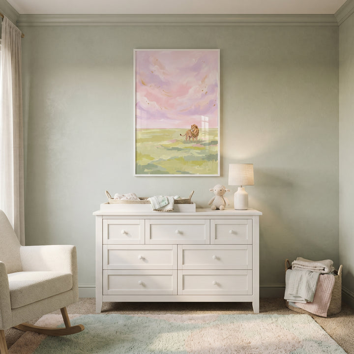 A lion stands in a grassy field looking back under a pastel pink sky safari lion wall art.