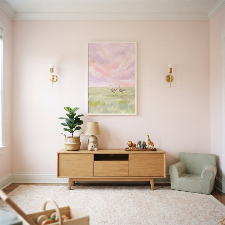 Pink sky walking ostrich animal wall art hangs above a wooden console in a soft pink room with a small green chair.