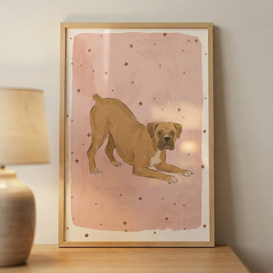 A vertical framed artwork featuring an illustration of a tan dog in a playful bowing position. The dog, which has a short muzzle and ears that fold forward, is captured with its front legs extended on the ground and its hind legs standing. This central figure is placed against a soft, textured pink background that has a slightly distressed appearance. 