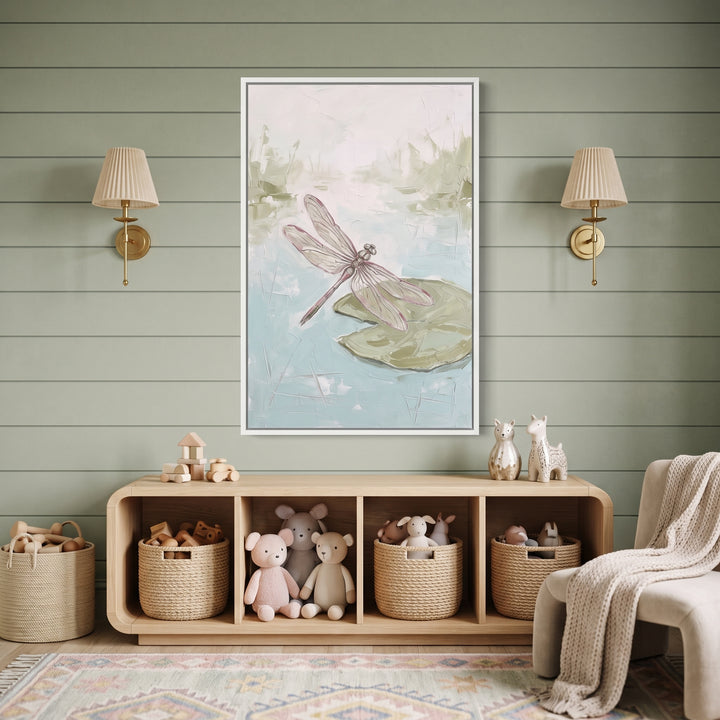 Pink wing textured dragonfly pond wall art hangs between gold sconces above a toy shelf in a sage green nursery.