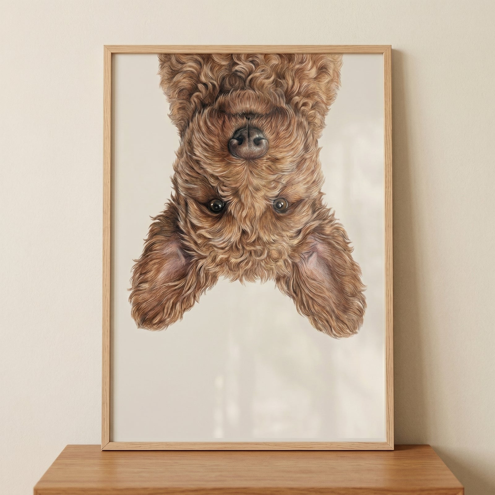 Upside-down curly dog peeks from the top of this playful brown poodle mix wall art in a light wood frame.