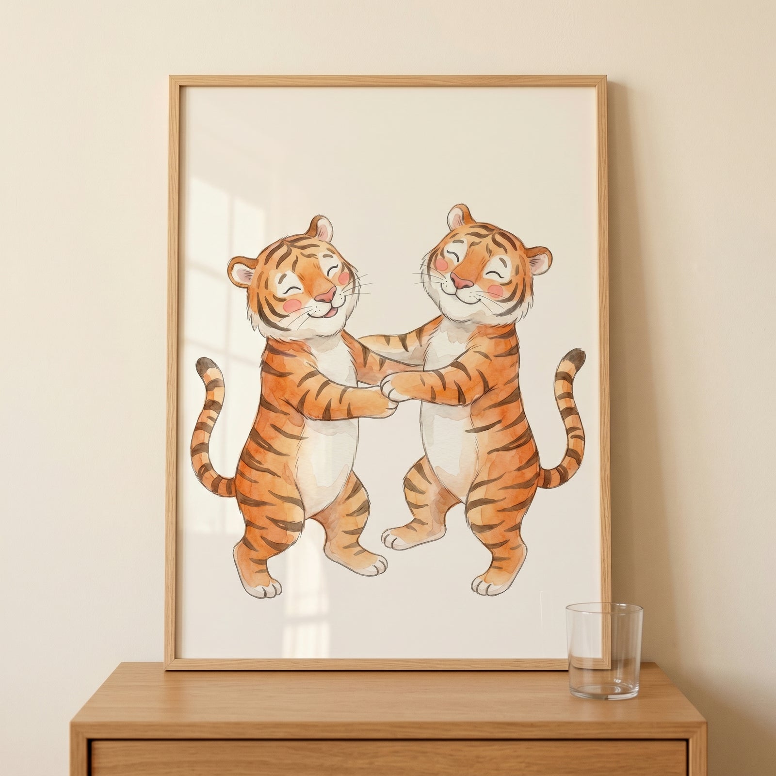 Two cartoon tigers hold paws in this playful orange dancing tiger wall art framed on a wooden dresser beside a glass.