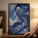 A framed digital illustration shows a white polar bear standing on a rocky mountain ledge, seen from behind. It wears a majestic, flowing blue cape with intricate gold filigree around the neck. The cape’s fabric merges into a vast, swirling galaxy filled with stars and nebulae. The bear looks out over soft clouds into a deep blue sky crowded with glowing stars. The artwork is held in a black frame, resting on a wooden table in a dimly lit room next to a soft light source.