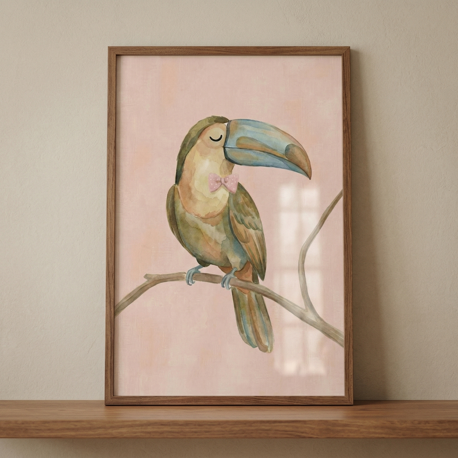 This image features a vertical, framed illustration of a toucan leaning against a plain wall on a wooden shelf. The bird is depicted with its eyes closed in a peaceful expression, perched on a simple brown branch. Its feathers are rendered in soft, muted shades of green and brown, and its large beak is a light blue color. A small, delicate pink bow is tied around the bird's neck. The background of the artwork is a solid, soft pastel pink. The piece is held in a thin, natural wood frame.
