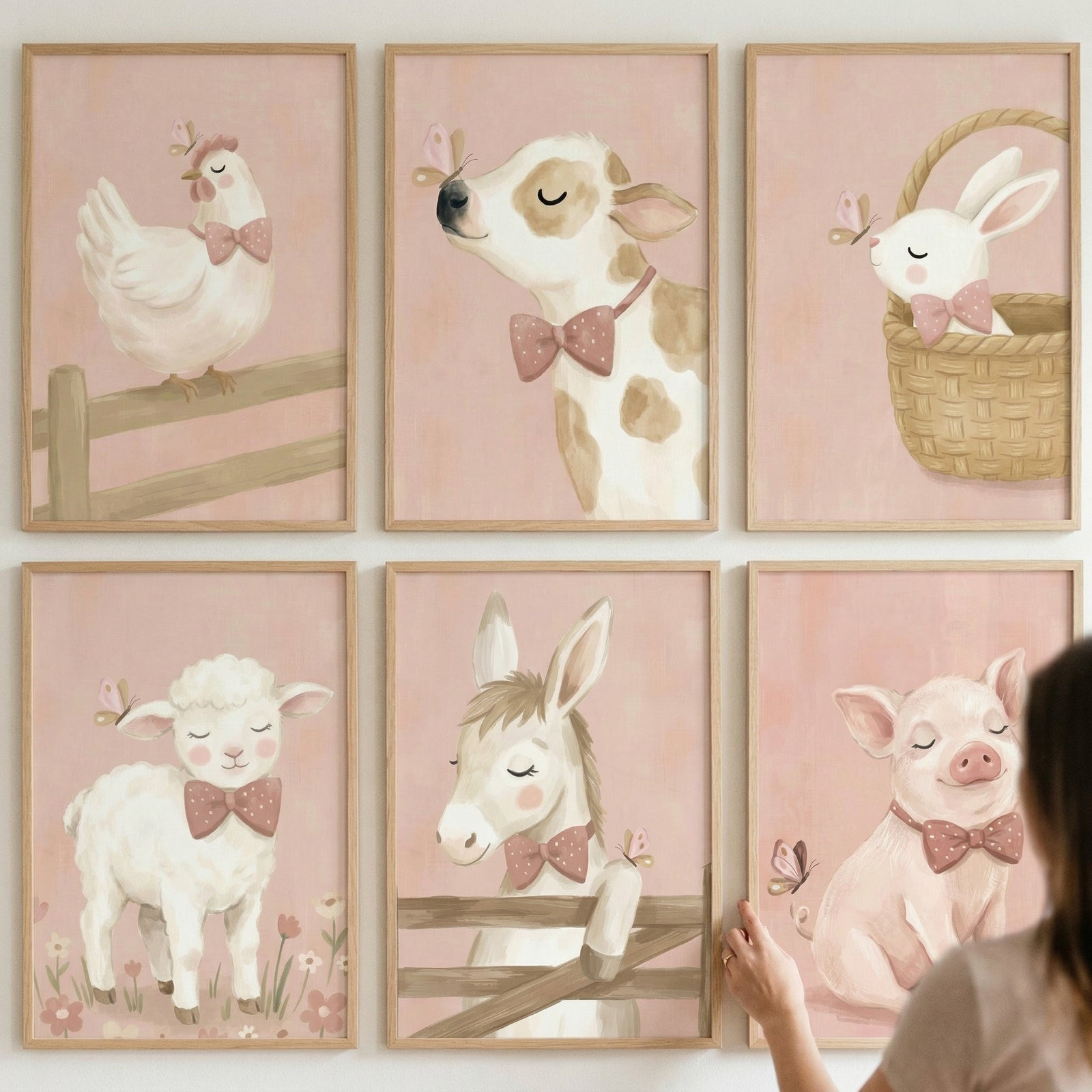 This collection of six framed illustrations displays a series of adorable baby farm animals against soft pink backdrops. Arranged in two rows of three on a light-colored wall, each piece features a different animal in a gentle, whimsical style.