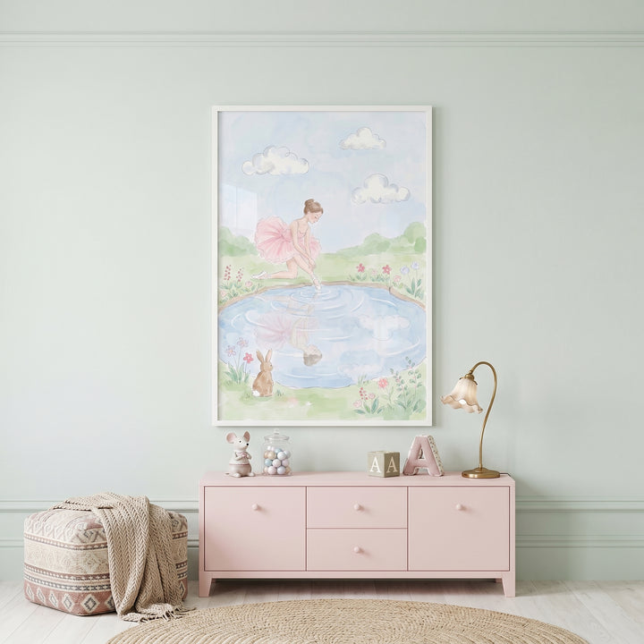 Pond reflection ballerina wall art hangs in a nursery with a pink dresser, a gold lamp, and a patterned ottoman.