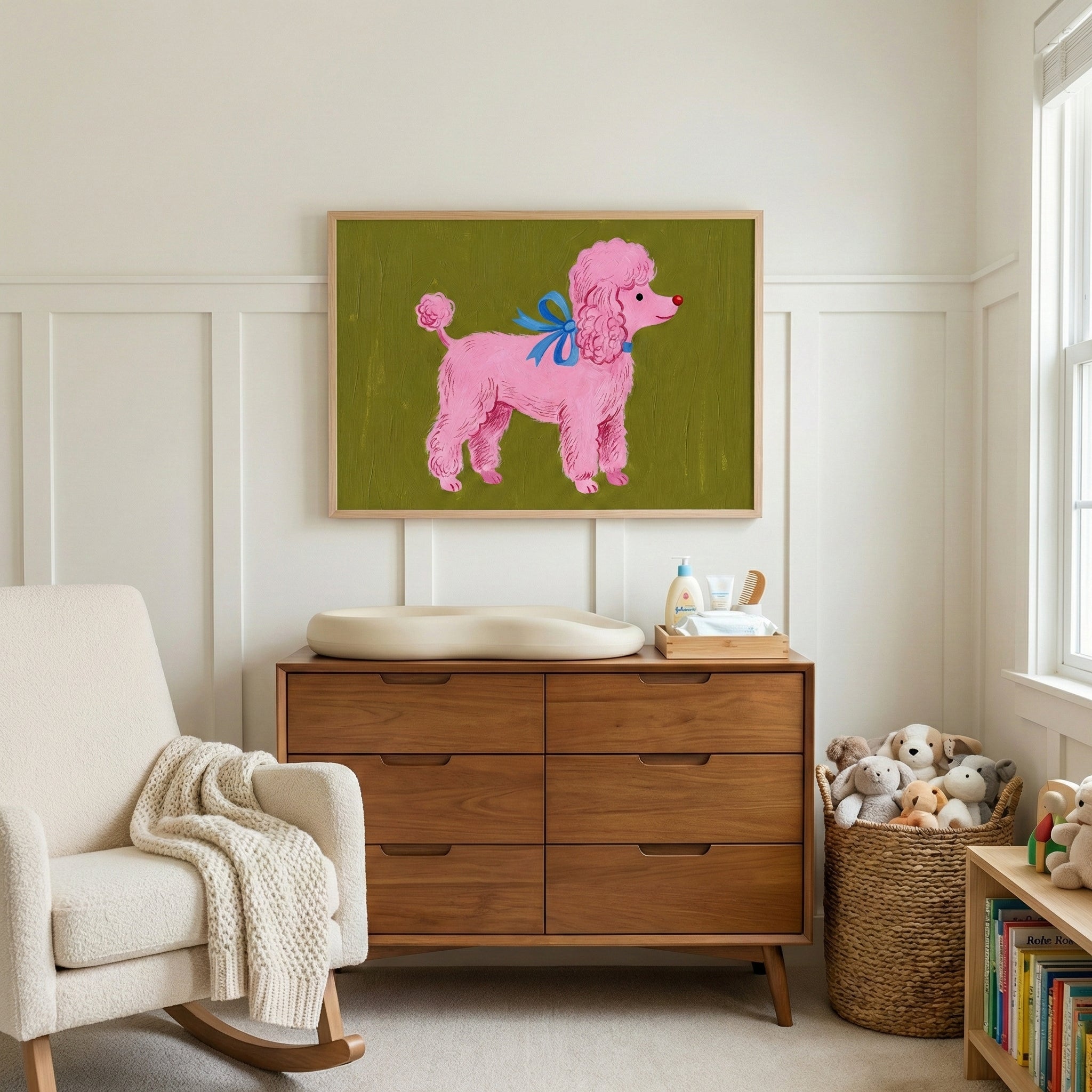 A framed illustration of a cheerful pink poodle with a blue bow adds a pop of fun to a nursery's warm wood furnishings and soft neutral palette. The dog’s cartoon-like charm brings personality and joy to the changing area.