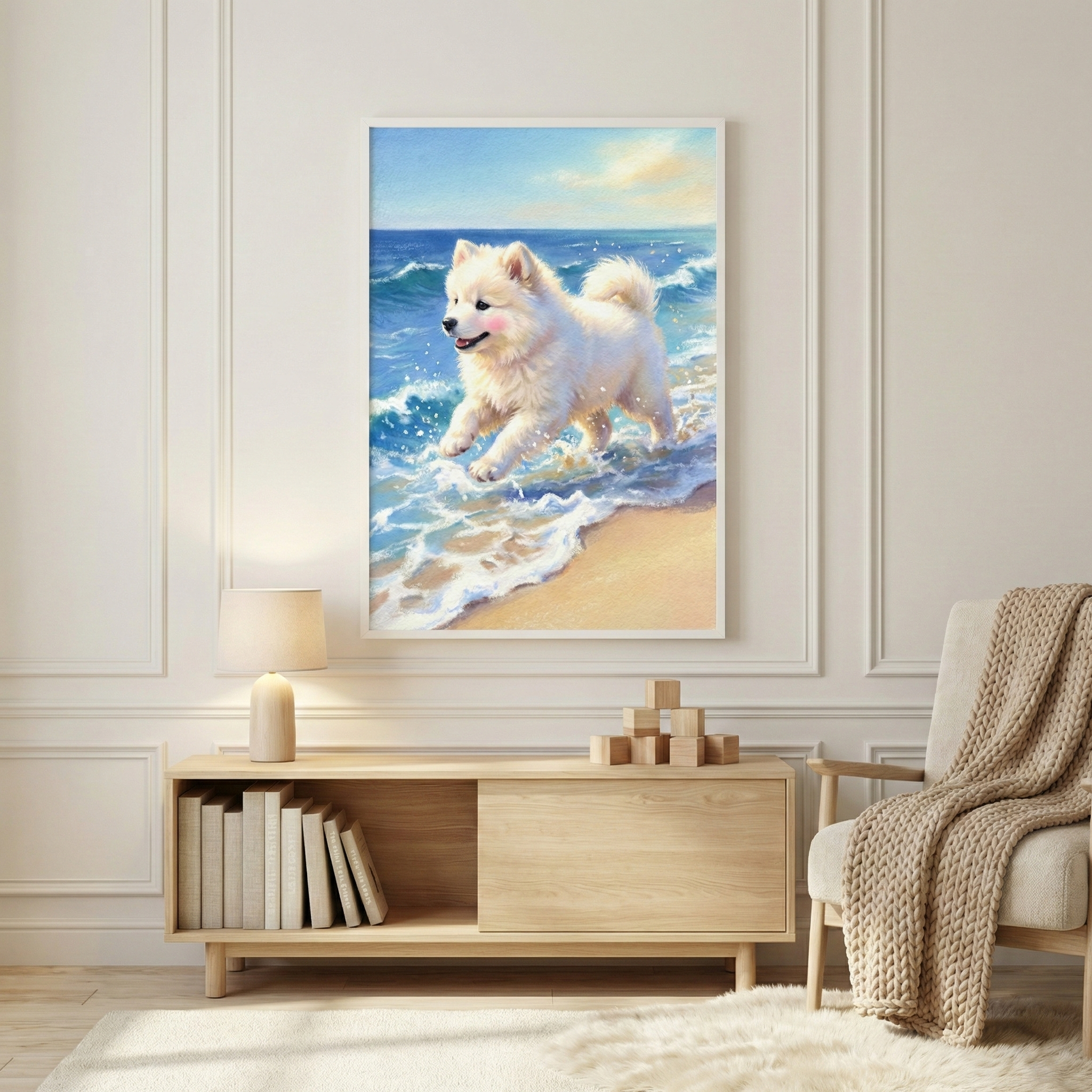 A framed piece of artwork hangs on a light-colored paneled wall in a modern interior. The artwork depicts a happy, fluffy white dog running through ocean waves along a sandy beach under a sunny sky. The dog has a joyous expression and pink cheeks as it splashes in the blue water. Below the art sits a light wood sideboard holding books, a glowing table lamp, and wooden blocks. To the right, a beige armchair is draped with a thick, textured knit throw.