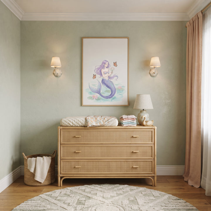 Purple hair butterfly mermaid wall art hangs above a woven dresser in a light green nursery with a round rug.