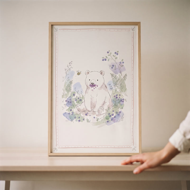 Framed purple mouth berry bear wall art of a cute white bear eating berries, displayed in a wooden frame on a table.