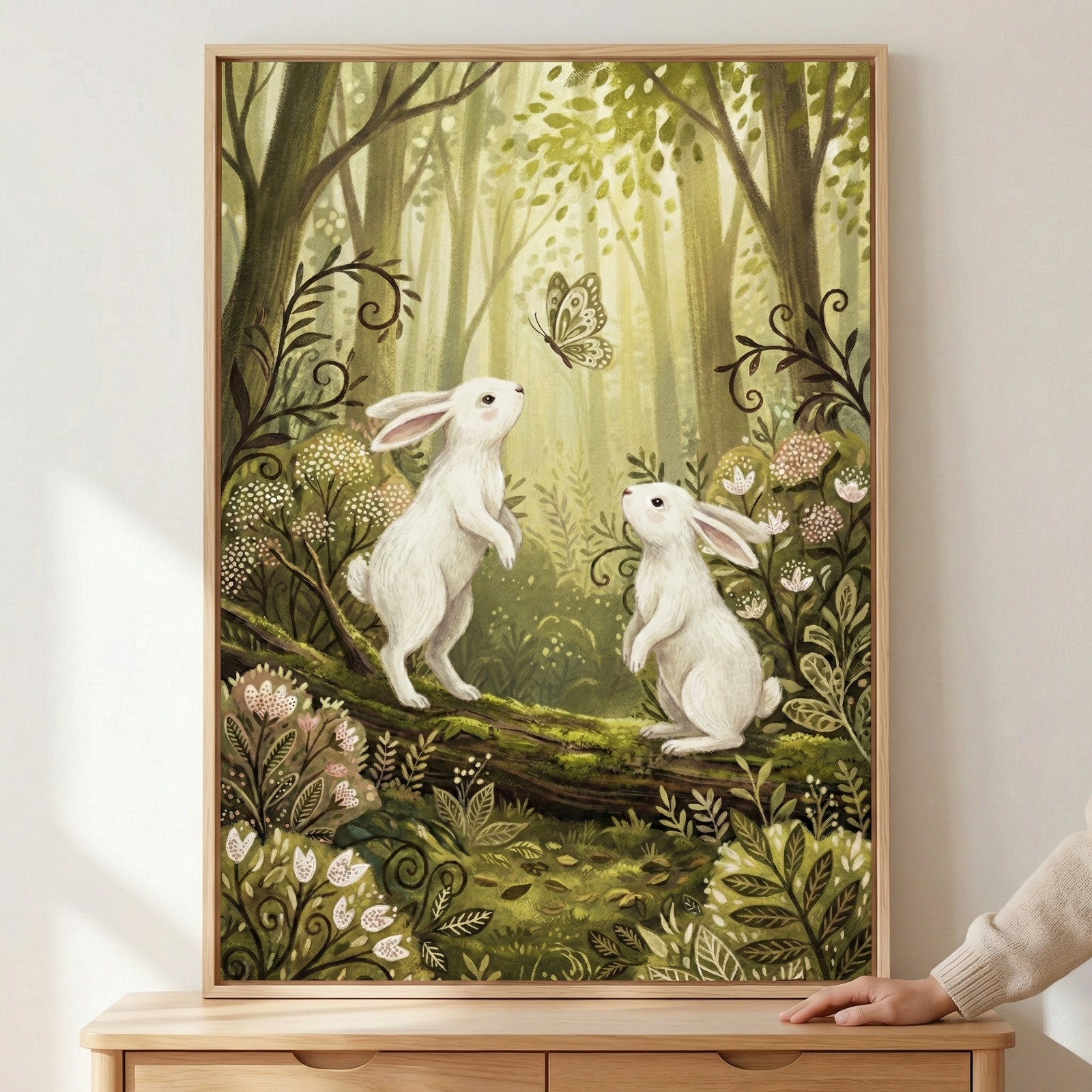 A framed painting depicts two white rabbits standing on their hind legs in a lush, enchanted forest, gazing at a delicate butterfly. The scene is surrounded by vibrant green foliage and blooming flowers, creating a whimsical and serene atmosphere.