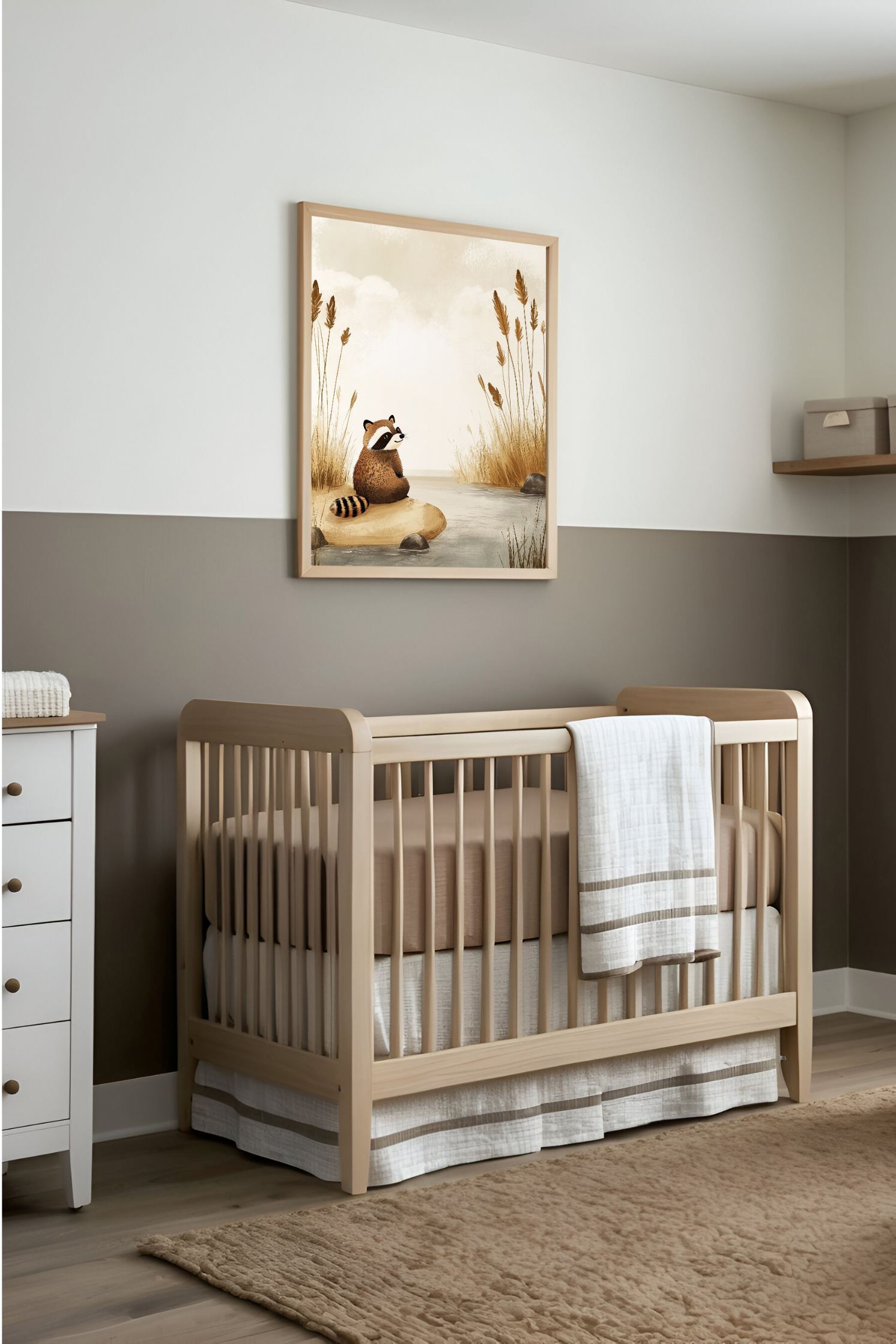 A minimalist nursery featuring a wooden crib with beige bedding against a taupe and white wall. Above the crib hangs a charming illustration of a raccoon sitting quietly on a rock by the water, enhancing the room’s calming, nature-inspired theme.