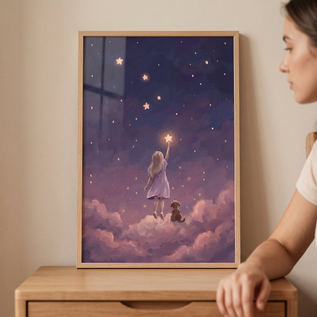 A woman looks at reaching for star girl space wall art of a girl and dog on clouds touching a glowing star.