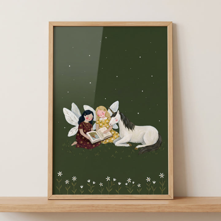 Framed reading storybook unicorn fairies wall art with two fairies and a unicorn reading under a starry night sky.