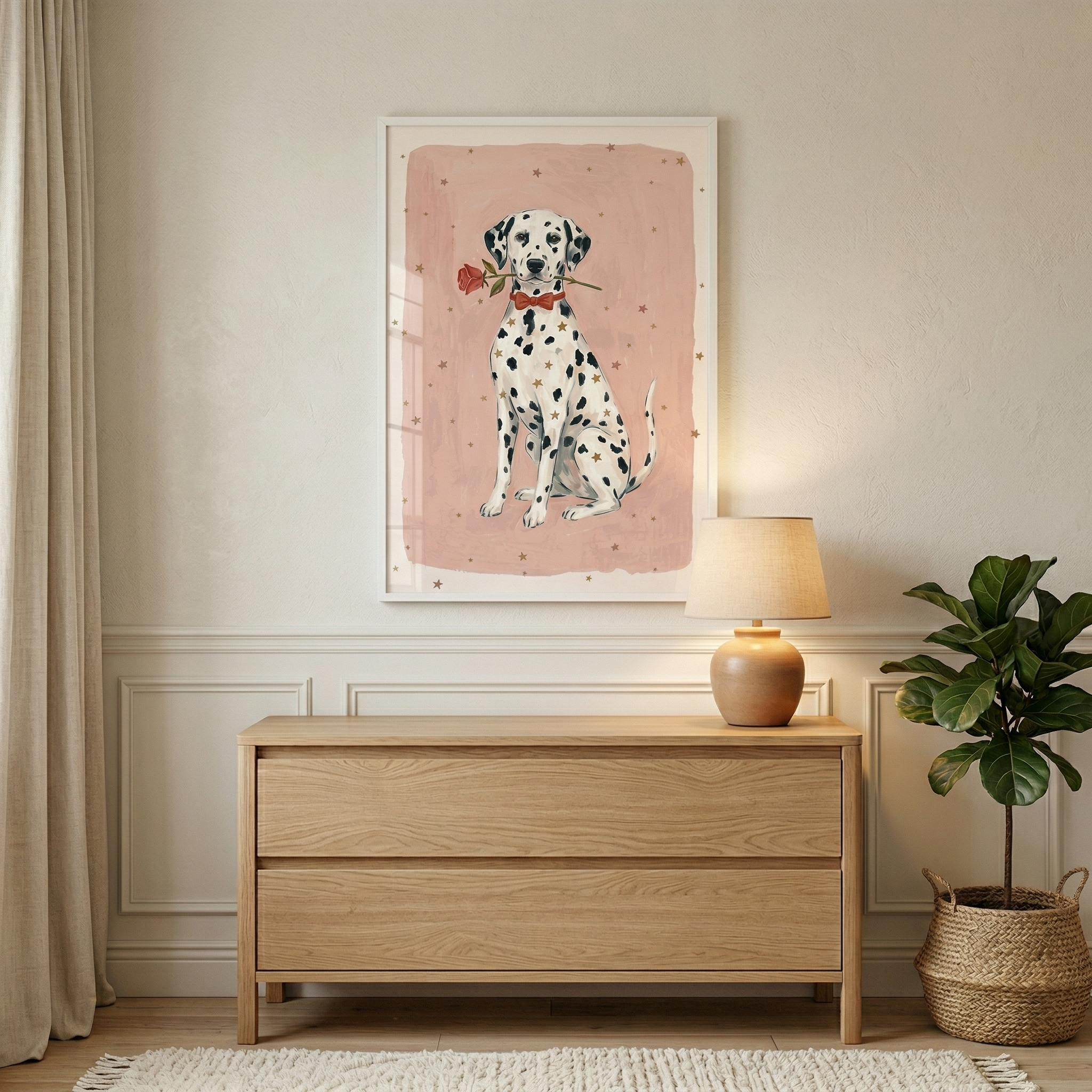 A cozy room interior features a framed illustration hanging on an off-white wall above a light-colored wood dresser. The artwork shows a spotted Dalmatian dog wearing a red bowtie and holding a red rose in its mouth. The background of the illustration is a soft pink rectangle decorated with small gold stars. On the dresser, a round lamp emits a warm light. Next to the furniture, a green leafy plant is in a woven basket. A beige curtain and a white rug complete the tranquil setting.