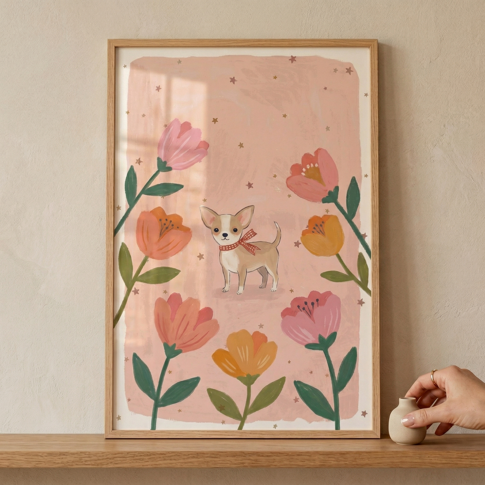A vertical framed illustration features a small, tan and white short-haired dog standing in the center. The dog has large, pointed ears and is wearing a red and white checkered neck scarf. Surrounding the dog are several large, stylized flowers in shades of coral, orange, and soft pink, each with dark green leaves and stems. The background is a textured light peach hue, embellished with many tiny, scattered gold stars. 