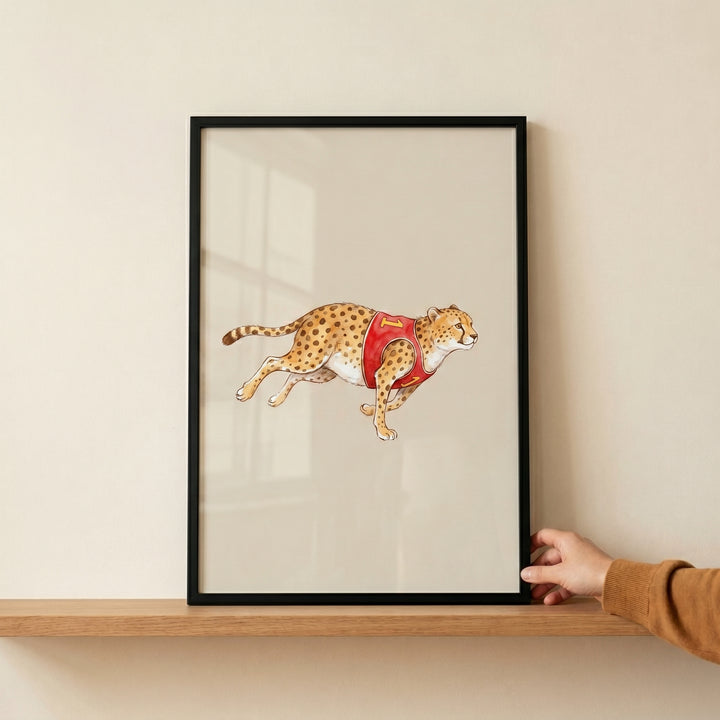 Framed red jersey running cheetah wall art resting on a wooden shelf and held by a hand.