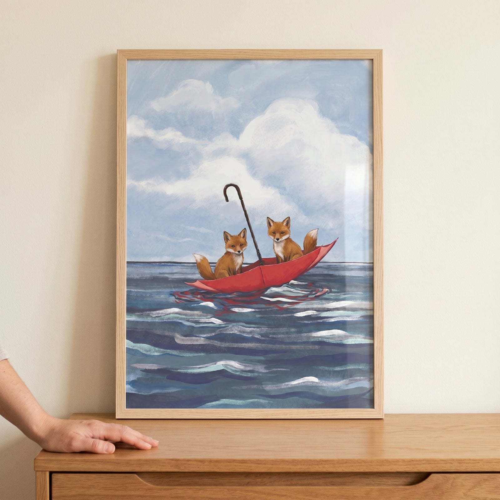 Two foxes in an upside-down red umbrella boat on blue ocean water under clouds, red umbrella boat fox wall art.