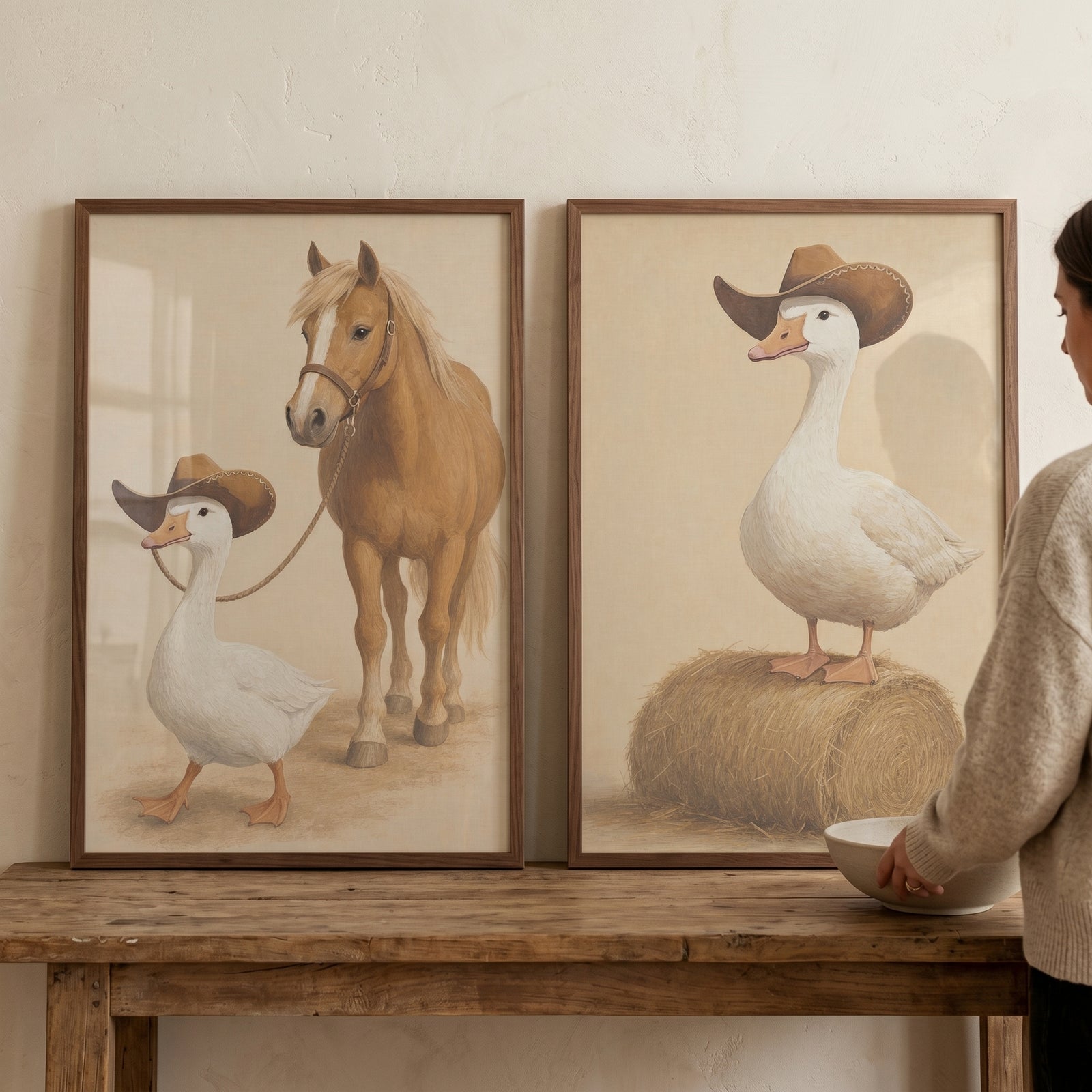 Refined country western goose wall art set of 2 shows geese in cowboy hats with a horse and hay bale on a wooden table.