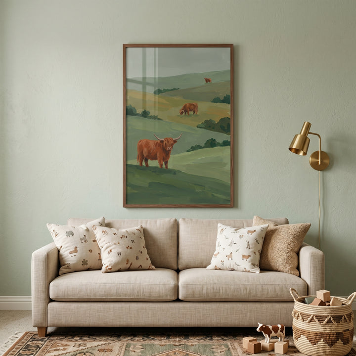 Rolling hill highland cow wall art hangs above a beige sofa with patterned pillows in a sage green room.