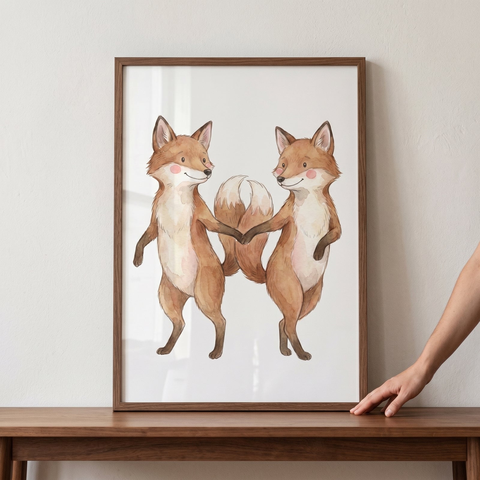 Rosy cheek dancing fox print with two watercolor foxes holding paws in a wooden frame on a table.