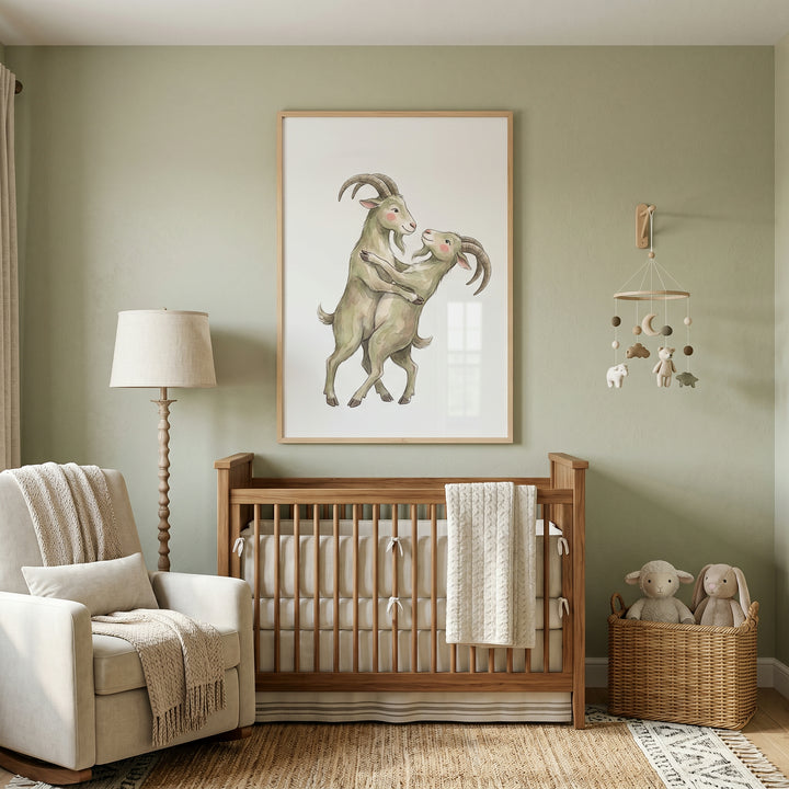 Nursery with a wooden crib, rocking chair, and rosy cheek dancing goats wall art hanging on a sage green wall.
