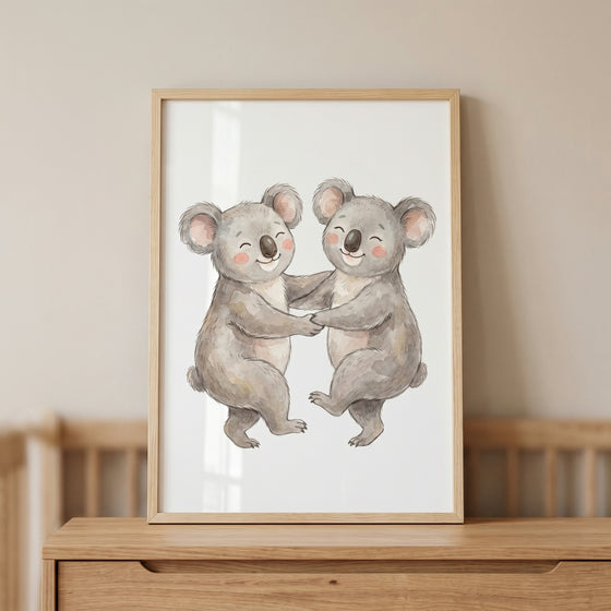 Rosy cheek dancing koala wall art in a light wood frame features two smiling watercolor koalas holding hands.