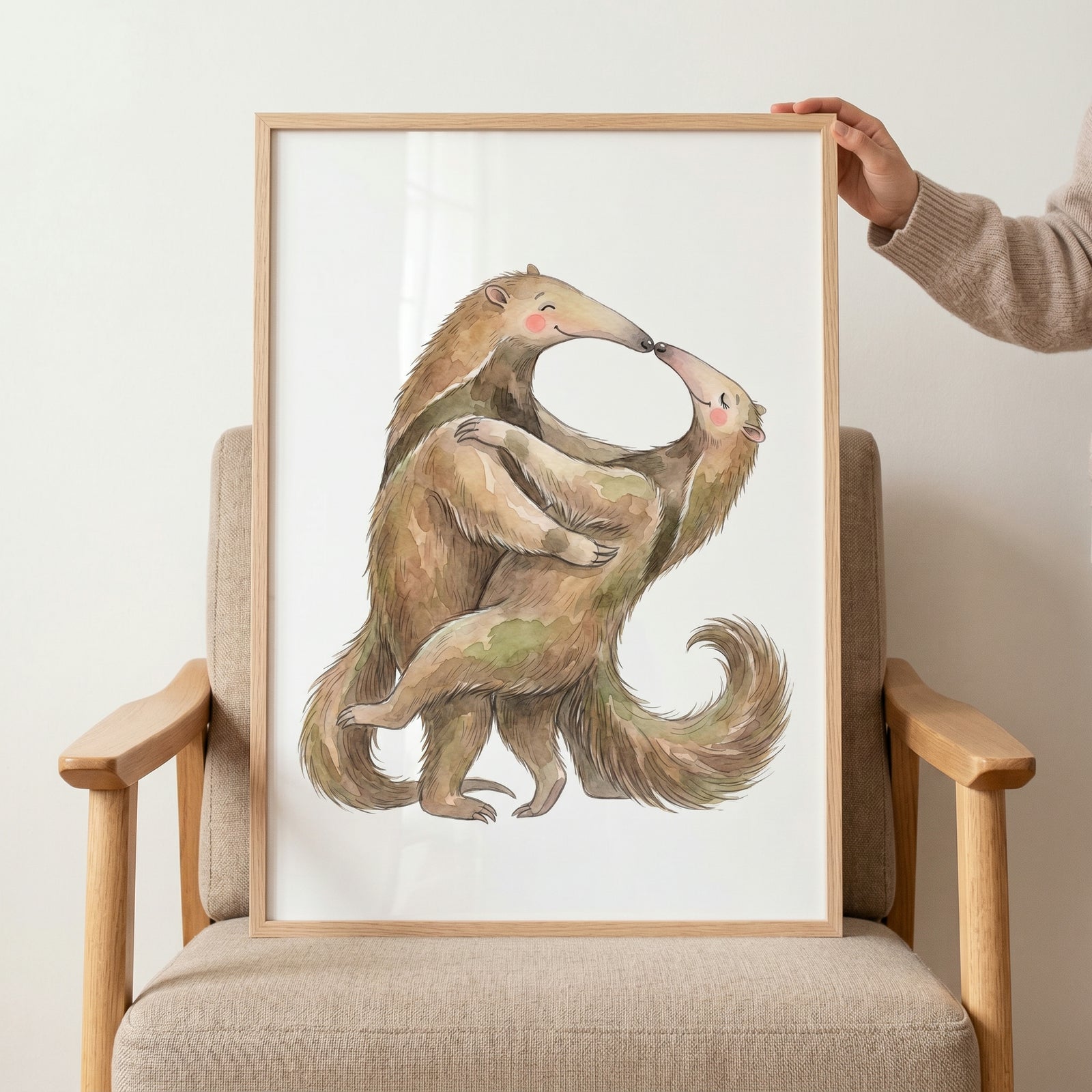 Rosy cheek hugging anteaters wall art shows two watercolor animals in an embrace, framed and resting on a chair.