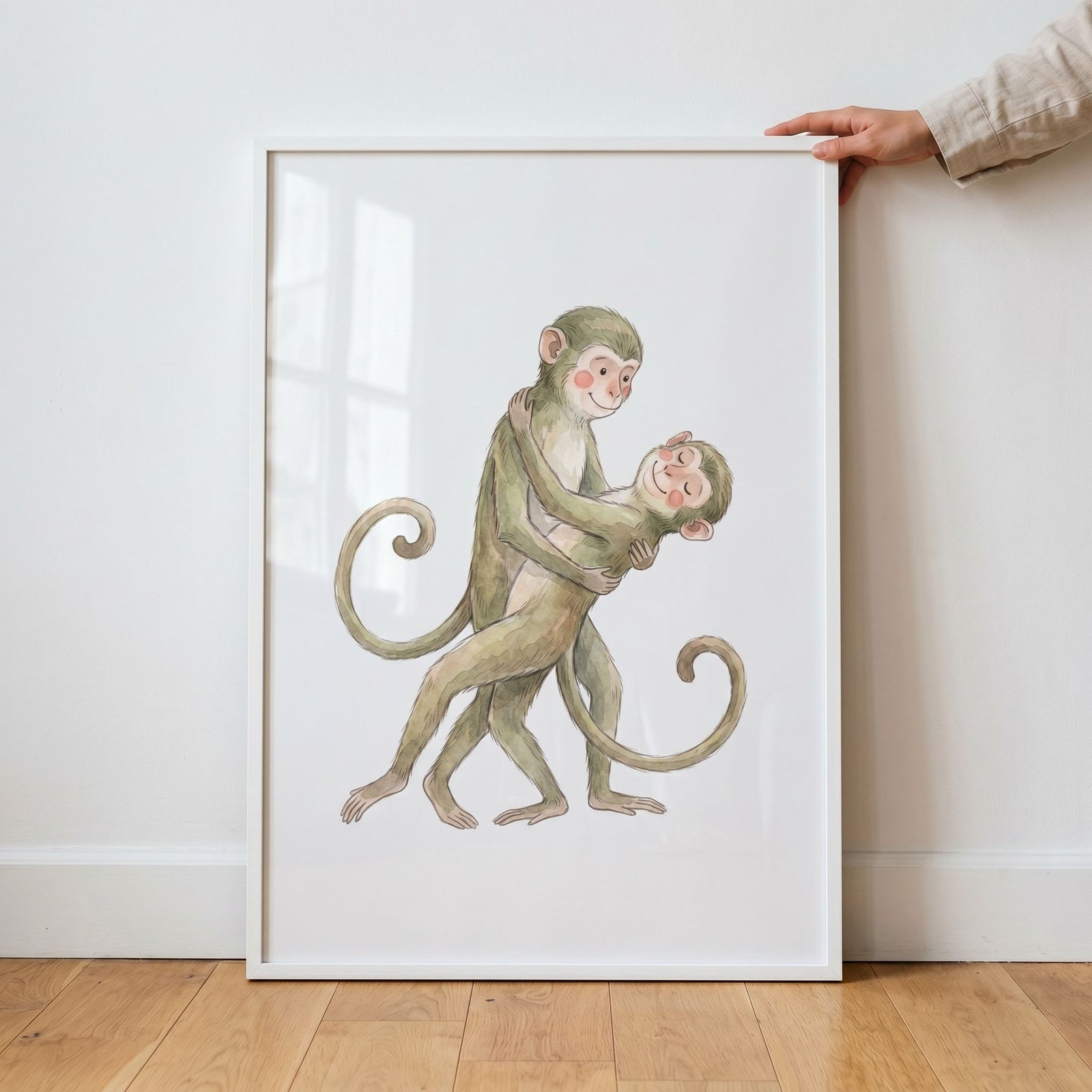 Framed rosy cheek hugging monkeys wall art shows two watercolor monkeys with long, curled tails in an embrace.