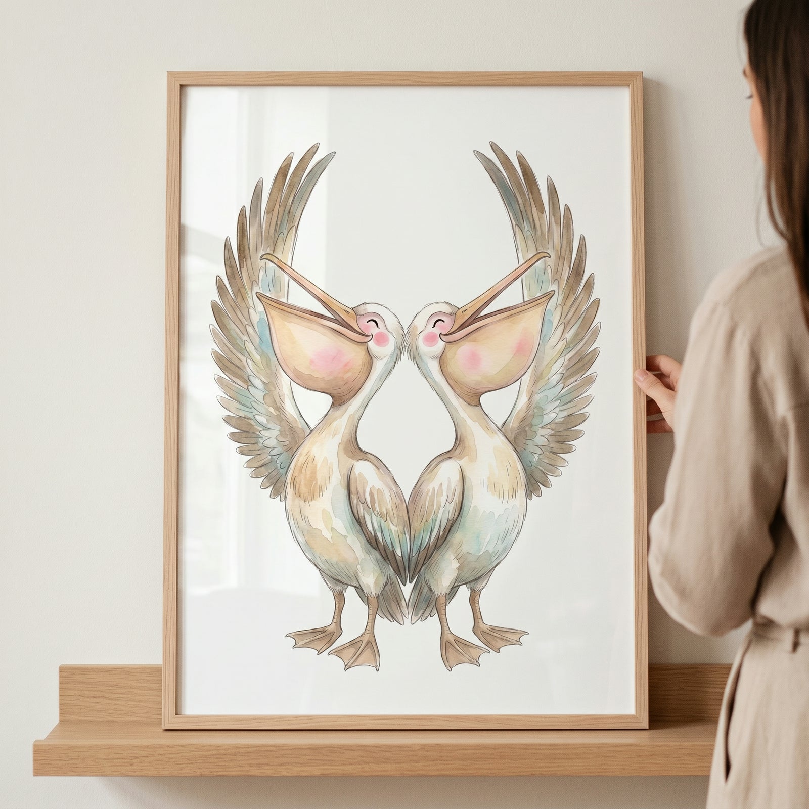 A person holds a framed rosy cheek singing pelicans artwork of two watercolor birds with spread wings and open beaks.