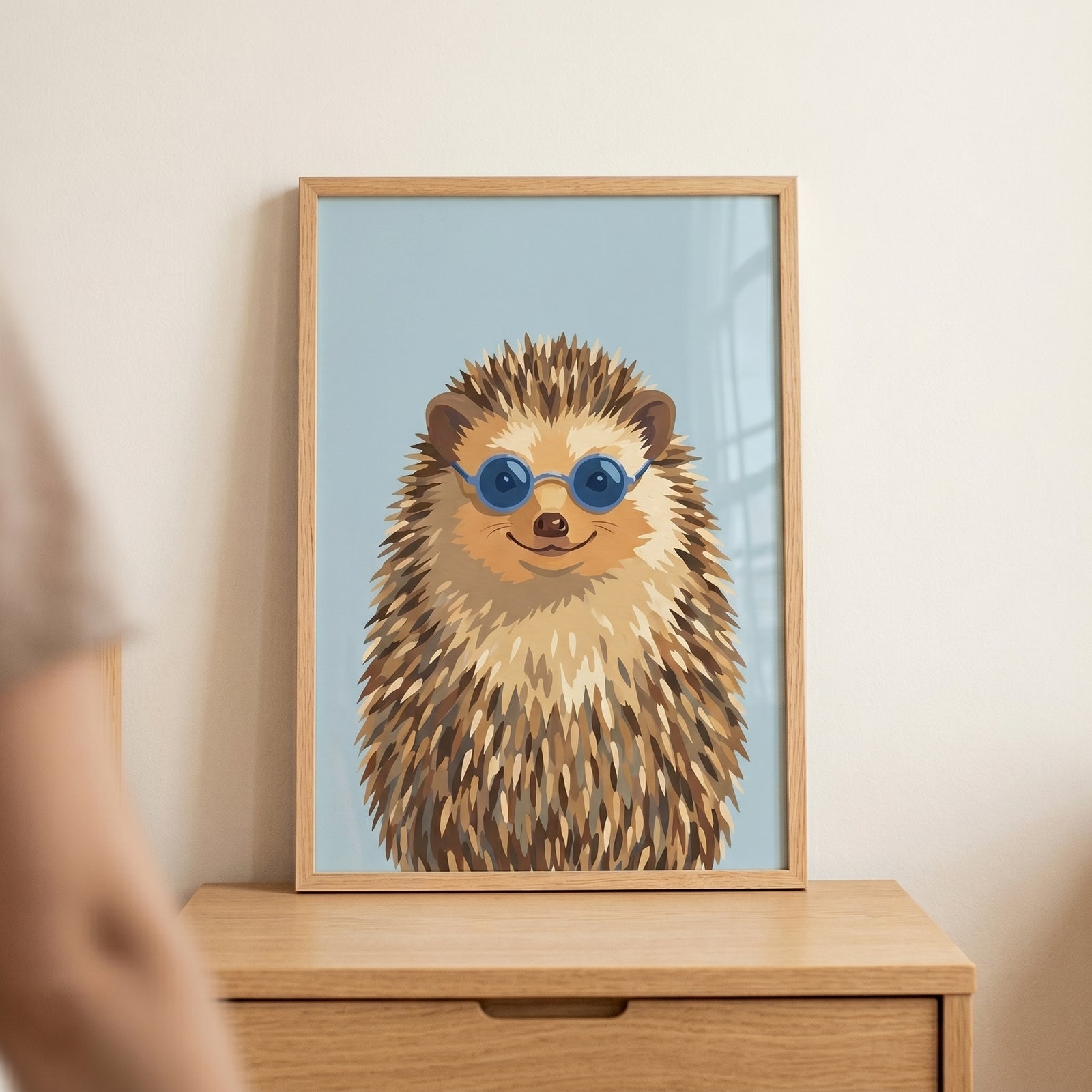Framed round blue shades hedgehog artwork sitting on a wooden dresser against a plain wall.