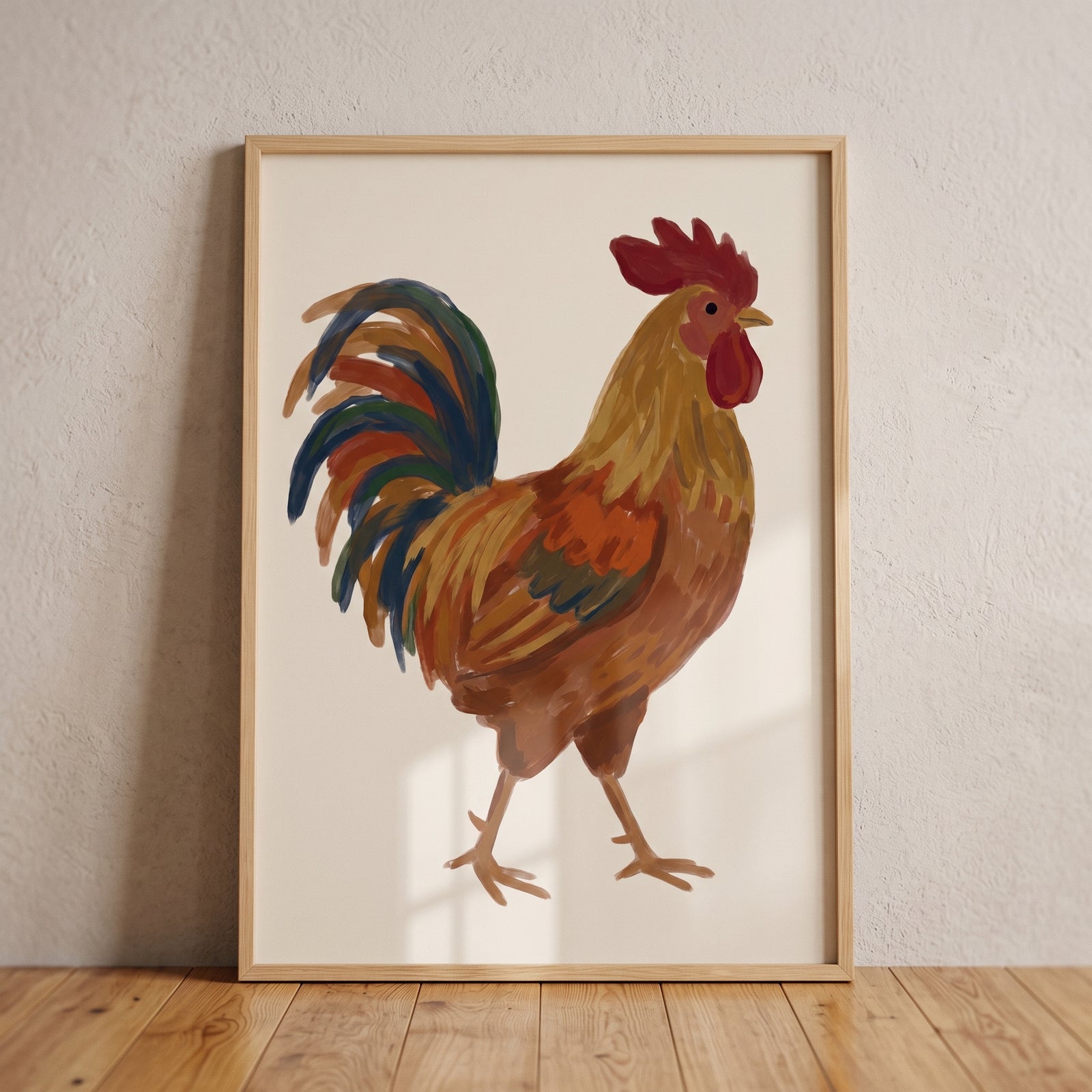Rustic orange brown rooster wall art in a light wood frame leaning against a textured wall on a wooden floor.