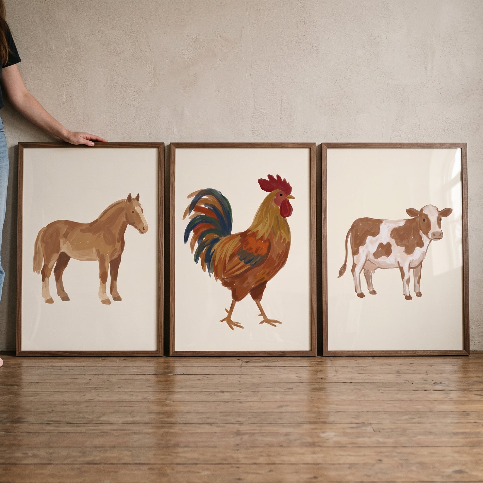 Rustic painterly farm animals wall art set of 3 featuring a horse, rooster, and cow in wooden frames on the floor.