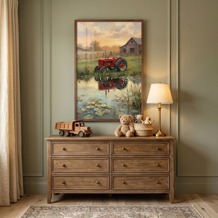 Rustic red farm tractor wall art hangs above a wooden dresser with a toy truck, teddy bear, and lamp in a green nursery.