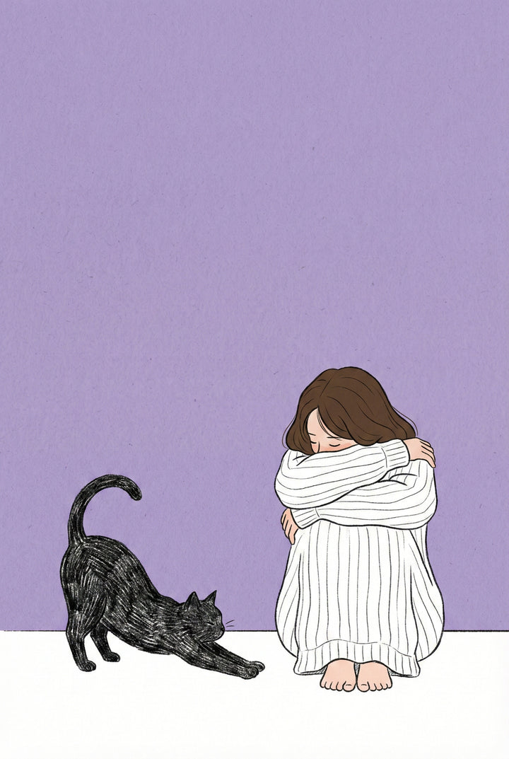 A girl sits with her head buried in her arms, knees pulled to her chest, while a black cat stretches beside her. The background is soft purple and quiet.