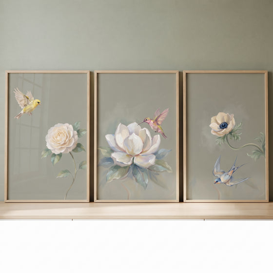 Sage floral garden bird wall art set of 3 with bird and flower illustrations in wooden frames on a green wall.