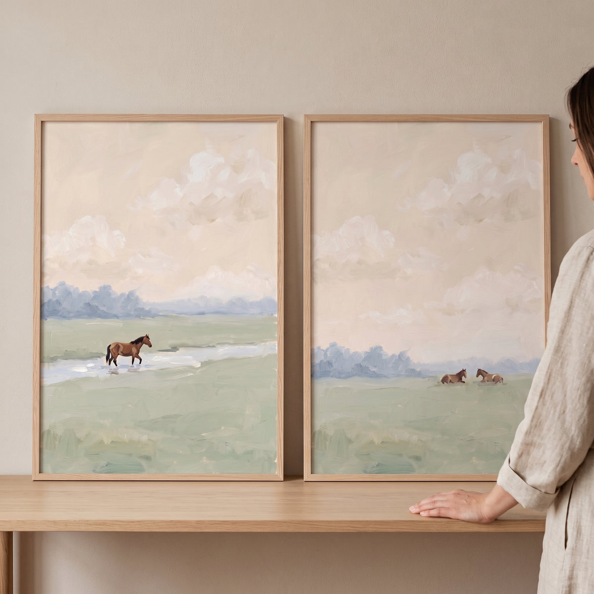 Sage green field horse wall art set of 2 shows horses in a soft landscape with a stream and pale sky in wooden frames.