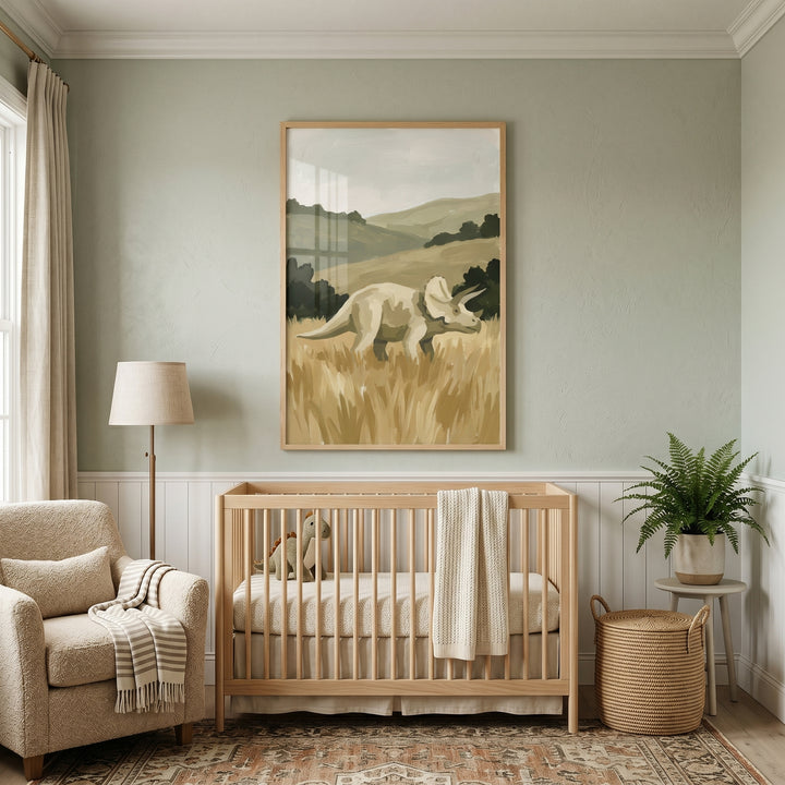 A nursery features a wooden crib, armchair, and sage green field triceratops artwork on a light green wall.