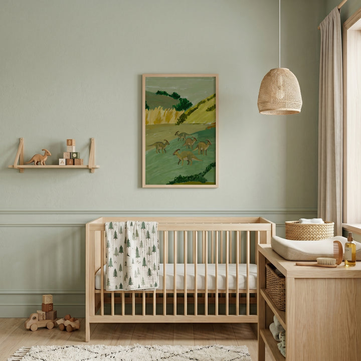 Sage green hill dinosaur artwork hangs above a wooden crib in a nursery with a wicker light and wooden toys.