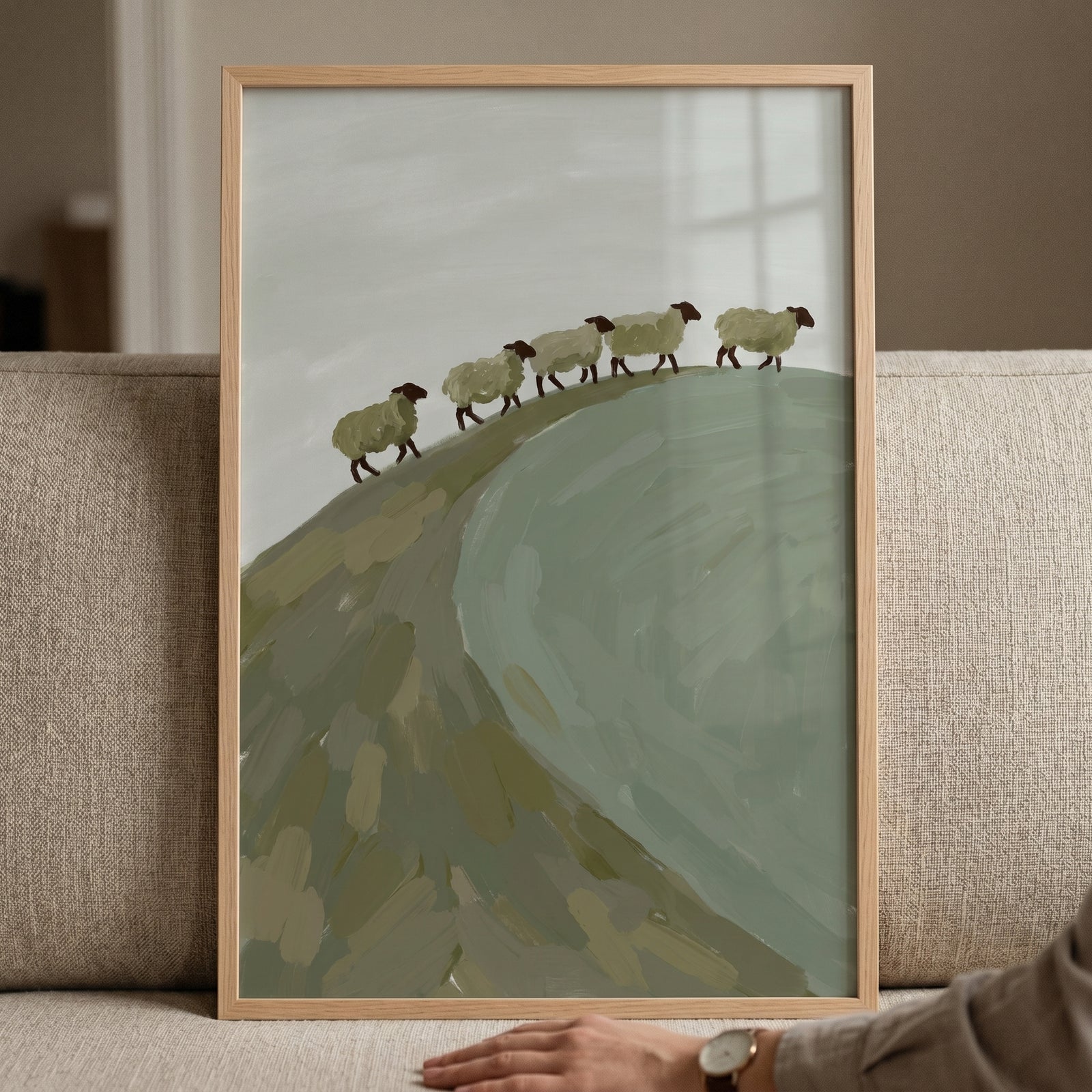 Sage green hill sheep wall art shows a row of five sheep walking along a grassy ridge in a light wood frame.