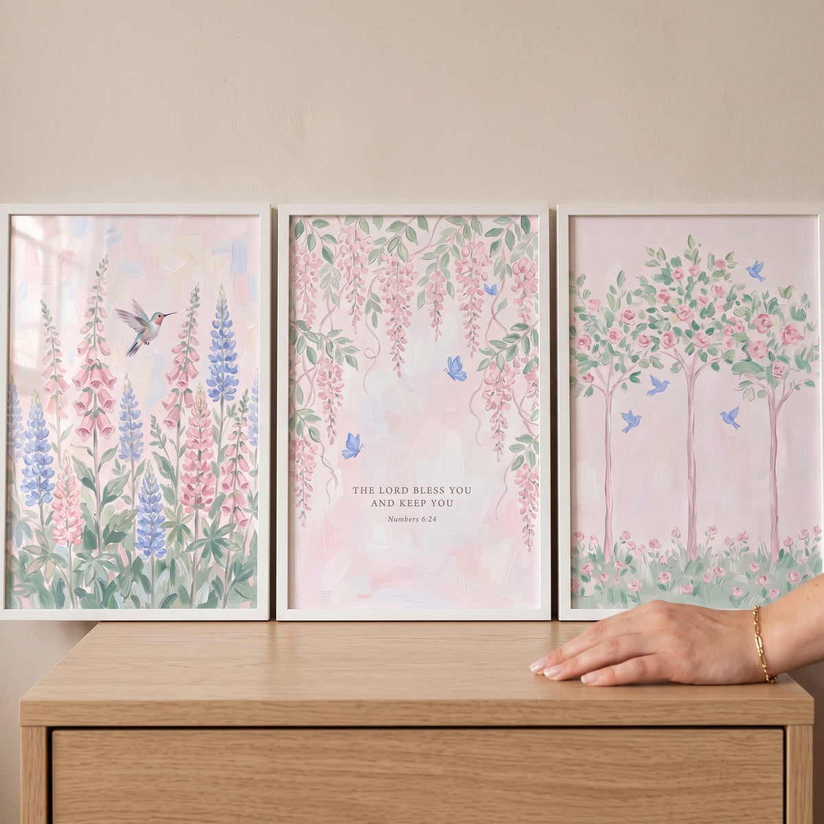 Sage green pink garden wall art set of 3 floral prints with a hummingbird and scripture on a light wood dresser.